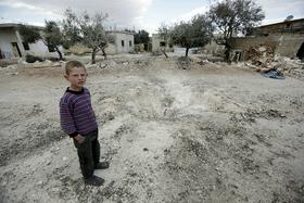 Deček sredi porušenega sirskega mesta. (Foto - Reuters)
