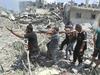Reševalci iz ruševin odnašajo truplo Palestinca.