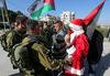 Ob božiču je skupina Palestincev proti izraelski okupaciji in izraelskemu nasilju nad Palestinci protestirala tako, da so se oblekli v Božičke in vojakom pred nosom mahali z zvončki. Foto: EPA