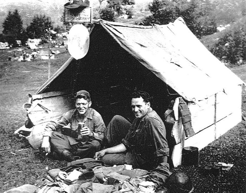 Ameriška vojaka v kampu v Logu pod Mangartom. Kjer ni bilo vojašnic ali drugih primernih bivališč, so zavezniški vojaki bivali v vojaških šotorih in zasilnih barakah. Janez Kavar - Denver Public Library; z dovoljenjem Tolminskega muzeja. Ameriška vojaka v kampu v Logu pod Mangartom. Kjer ni bilo vojašnic ali drugih primernih bivališč, so zavezniški vojaki bivali v vojaških šotorih in zasilnih barakah. Janez Kavar - Denver Public Library; z dovoljenjem Tolminskega muzeja.