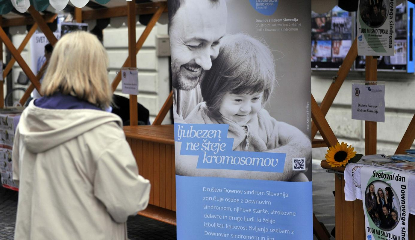 Opis fotografije: Na fotografiji je stojnica, na kateri je plakat ob svetovnem dnevu Downovega sindroma, prikazuje očka s hčerkico z DS, krasi pa ga še napis: ljubezen ne šteje kromosomov. Foto: Bobo Opis fotografije: Na fotografiji je stojnica, na kateri je plakat ob svetovnem dnevu Downovega sindroma, prikazuje očka s hčerkico z DS, krasi pa ga še napis: ljubezen ne šteje kromosomov. Foto: Bobo
