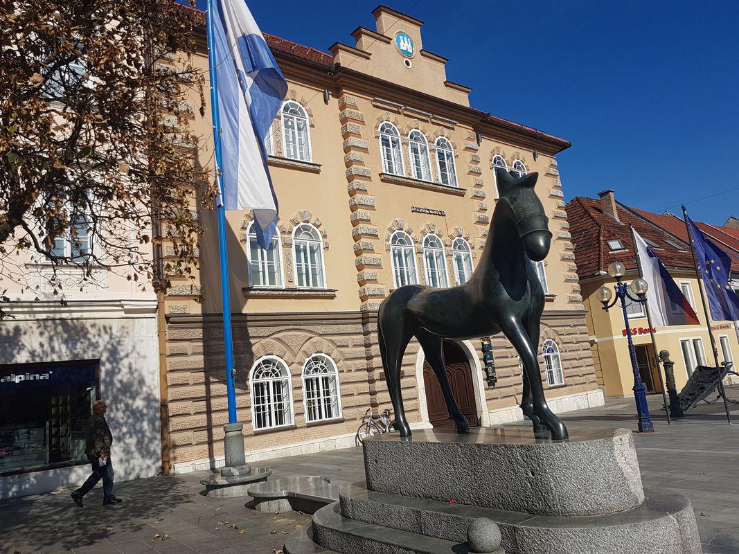 Na fotografiji je stavba Mestne občine Slovenj Gradec, pred njo je črn kip konja. Foto: Gorazd Kosmač, arhiv MMC RTV SLO Na fotografiji je stavba Mestne občine Slovenj Gradec, pred njo je črn kip konja. Foto: Gorazd Kosmač, arhiv MMC RTV SLO