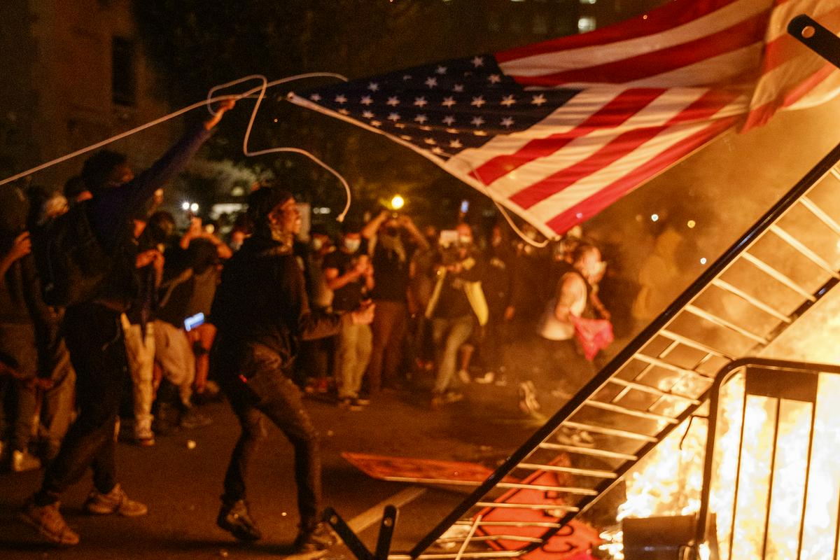 Med protesti blizu Bele hiše je na ognju končala tudi ameriška zastava. Foto: EPA Med protesti blizu Bele hiše je na ognju končala tudi ameriška zastava. Foto: EPA