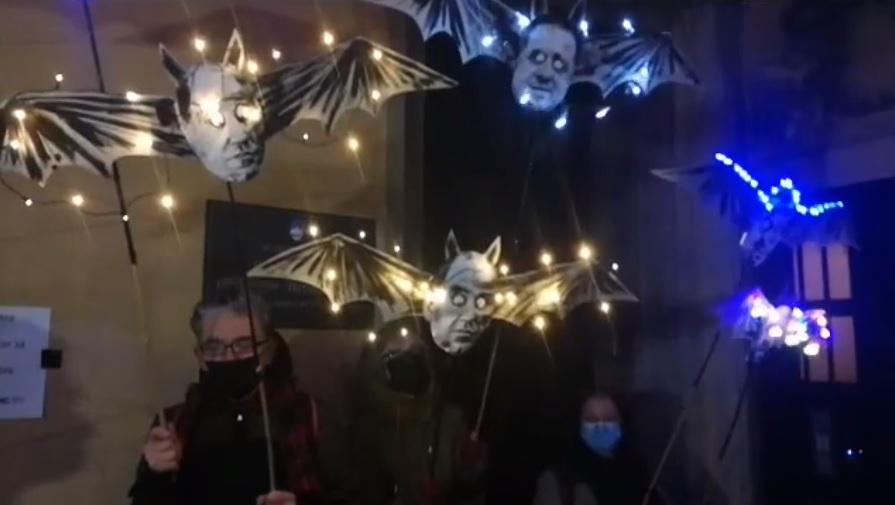 Protestniki z maskotami netopirjev pred vhodom na sedež stranke SMC. Pred vrata so stresli česen, da bo odgnal Protestniki z maskotami netopirjev pred vhodom na sedež stranke SMC. Pred vrata so stresli česen, da bo odgnal